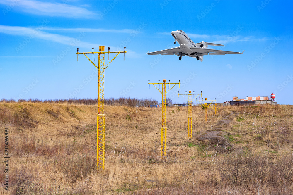 The aircraft prepare to landing, flying above the metal supports with navigation signal lights The aircraft prepare to landing, flying above the metal supports with navigation signal lights