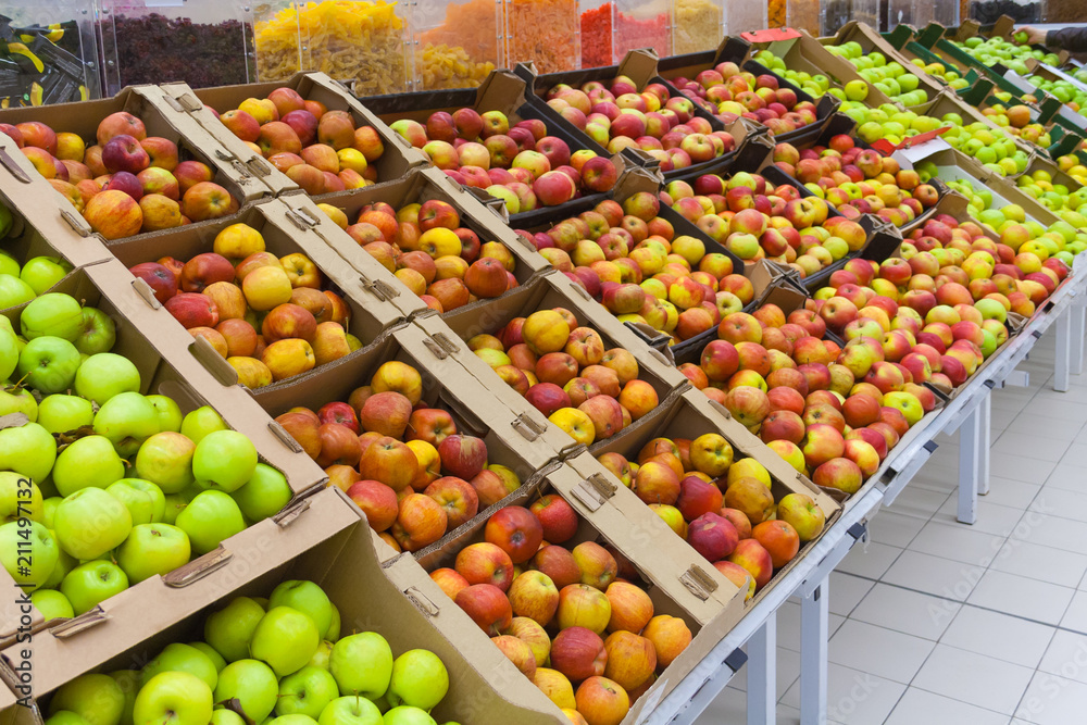 Perspective view of a pile of apples in the cartons boxes on the racks in supermarket