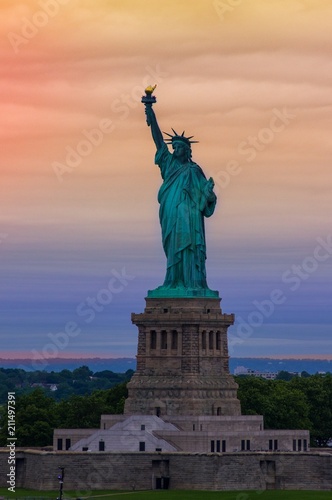 Statue of Liberty with graduated orange and purple sunset in the background