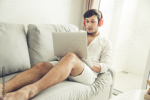 Happy man relaxing on the sofa listening to music with laptop at home