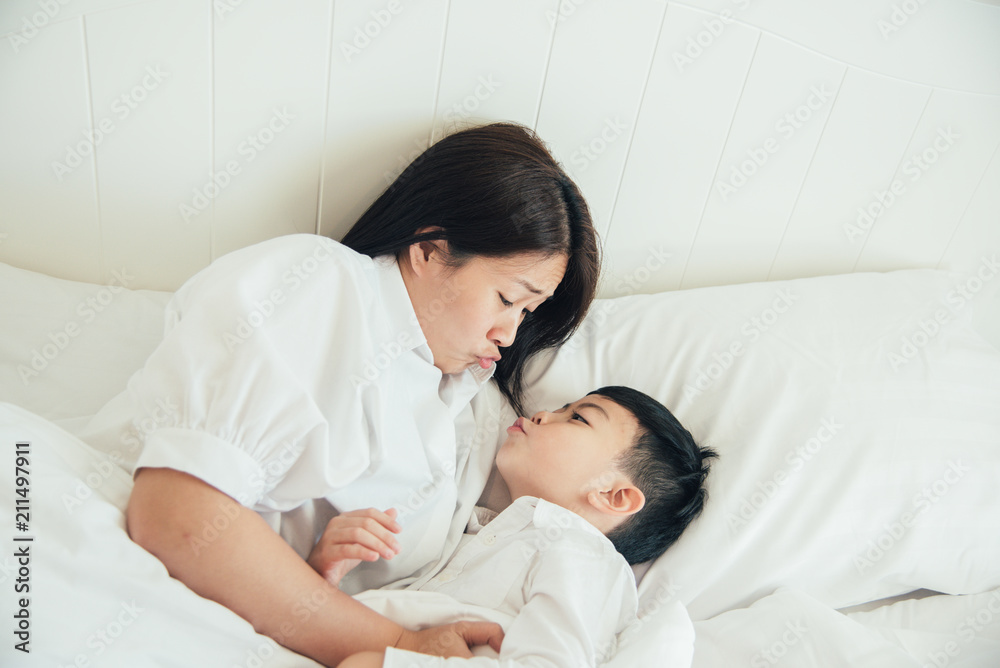 Happy loving family. Mother and her son playing on the bed in bedroom.