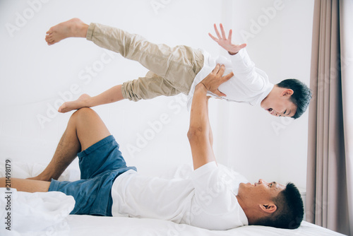 Happy family. Dad and son playing and laughing in bed room.