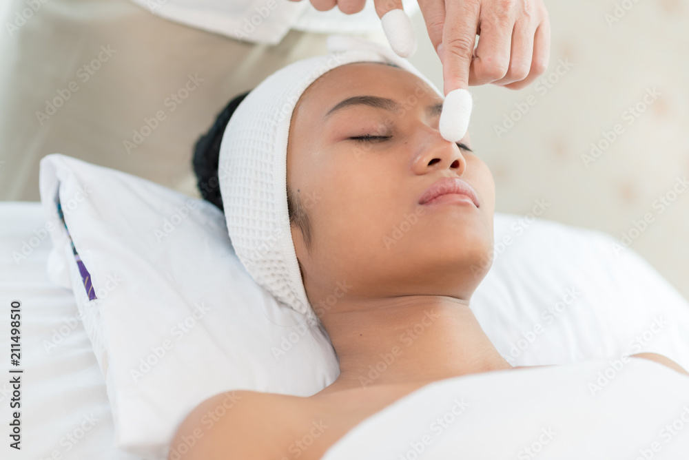 Young asian woman enjoying face massage in luxurious beauty salon.