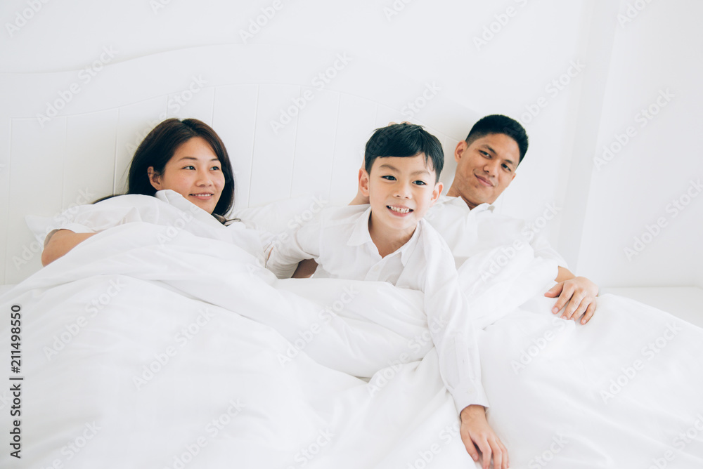 Happy aian family lying in bed and sleeping.