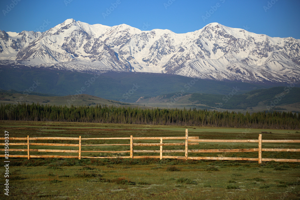 Wooden fence from the parallel boards in mountains covered by a snow