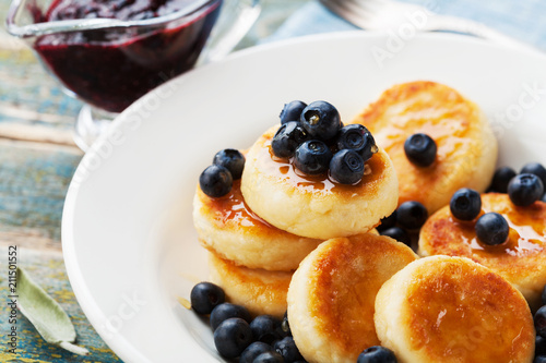 Delicious cottage cheese pancakes or curd fritters decorated honey and blueberry. Healthy and diet breakfast.