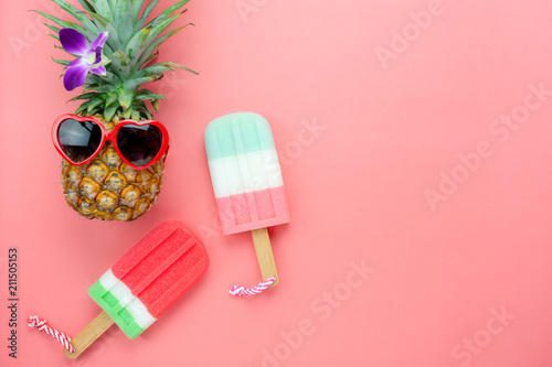 Table top view aerial image of summer & travel beach holiday in the season background concept.Flat lay sign objects food on season for travel.pineapple wear sunglasses with ice cream on pink paper.