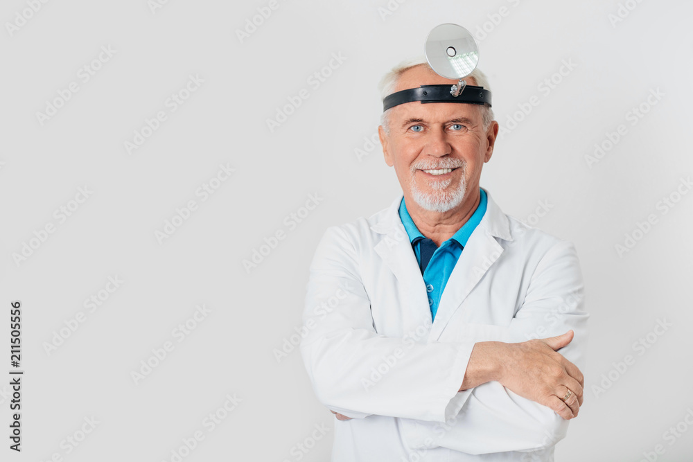 smiling ENT doctor, elderly man standing at light background smiling ENT doctor, elderly man standing at light background
