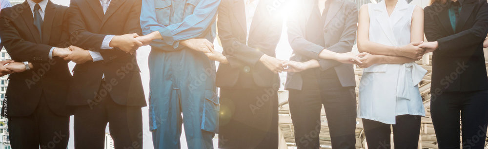 Midsection Of Colleagues With Holding Hands Standing In City