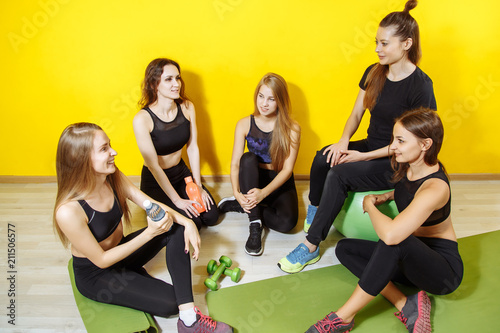 Smiling group of friends in sportswear talking during rest in a gym