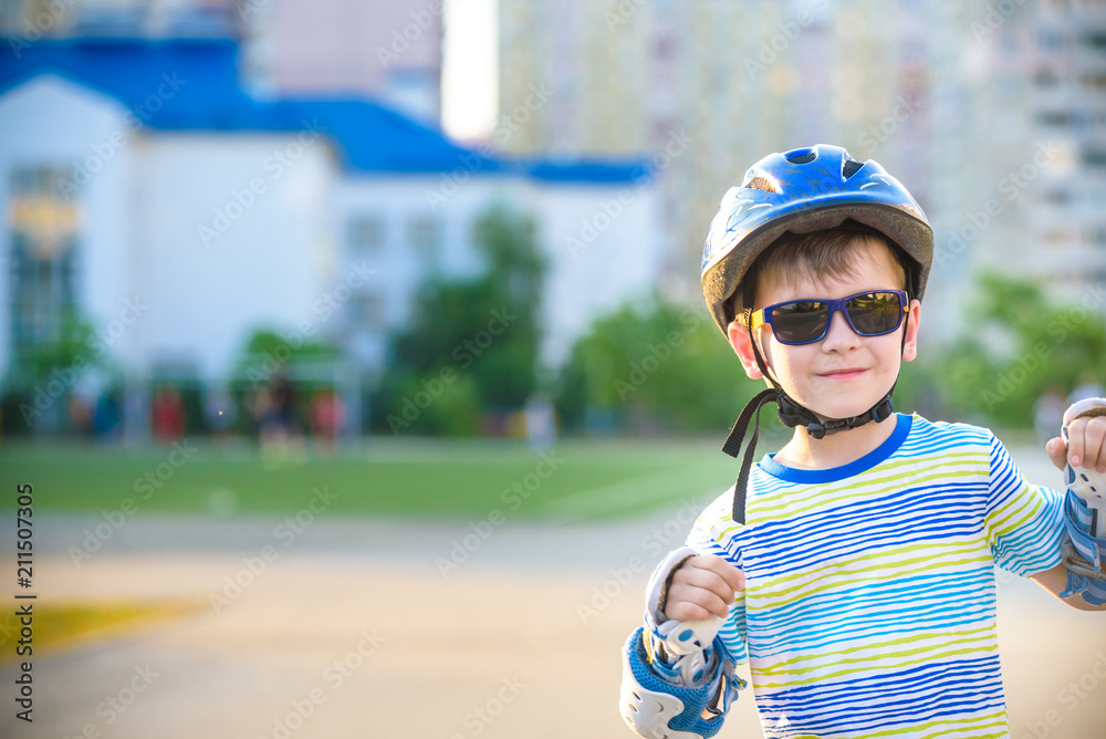 Little boy riding on rollers in the summer in the Park. Happy child in helmet learning to skate. Safety in sport