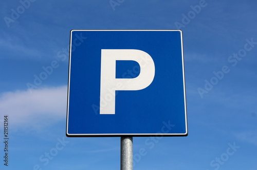Parking sign with cloudy blue sky background on warm sunny day