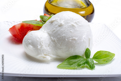 Fresh soft Italian white cheese mozzarella buffalo, original from Campania, Paestrum and Foggia regions, South Italy, served with tomatoes, fresh basil and olive oil