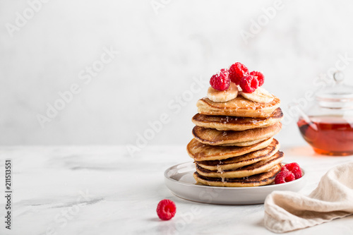 Stack of homemade pancakes with fresh raspberries on light concrete background, copy space photo