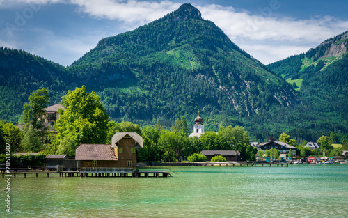 Fototapeta Naklejka Na Ścianę i Meble -  Boathouse on the Wolfgangsee with Mountains in the Background and clouds on the sky