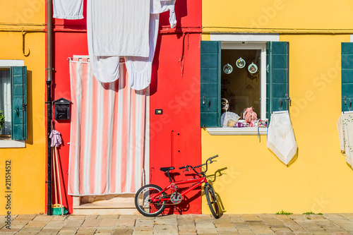 Yellow and red house with a bicycle. Colorful houses in Burano island near Venice, Italy. Venice postcard. Famous place for european tourism and travel