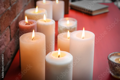 Many burning candles on wooden table