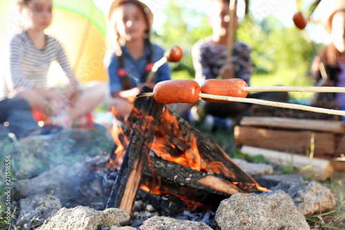 Frying sausages on bonfire, closeup. Summer camp