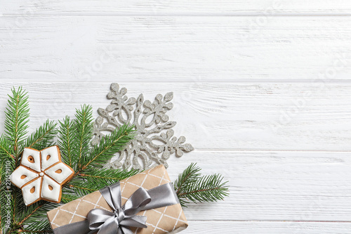 Flat lay composition with Christmas gift and fir branches on wooden background