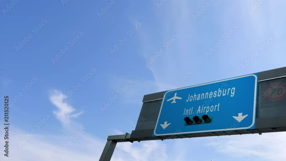 airplane flying over johannesburg airport signboard