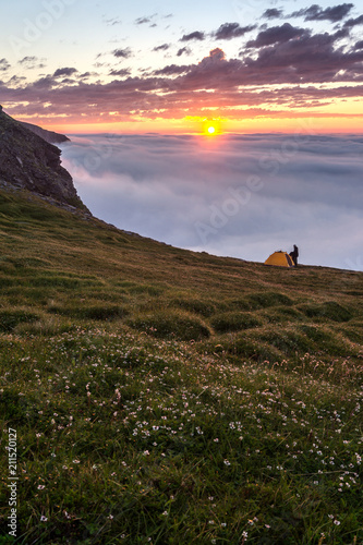 Man with tent at sunset on the mountains of Soroya island, Norway photo