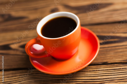 Full orange ceramic mug of black coffee on old wooden brown table