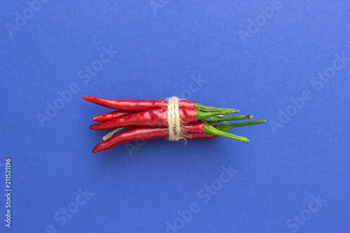 top view, red chili pepper, tied with braid on a blue background, horizontally located photo