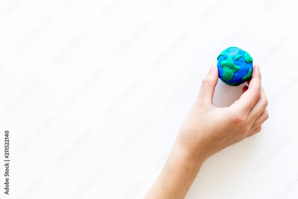 Earth. Hand hold plastiline symbol of planet Earth globe on white background top view copy space Earth. Hand hold plastiline symbol of planet Earth globe on white background top view copy space