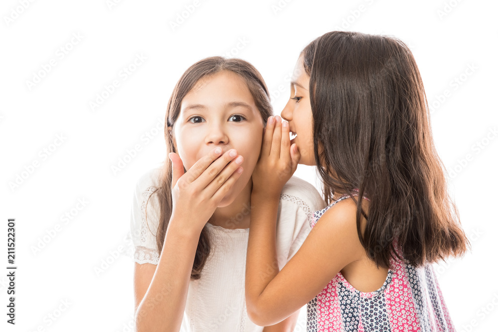 Younger sister whispering news to older sister's ear Younger sister whispering news to older sister's ear