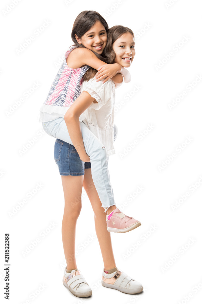 Young girl carrying sister giving piggyback ride Stock Photo