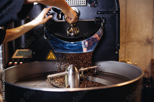 Slika na platnu Freshly roasted coffee beans pouring from a large coffee roaster into the cooling cylinder