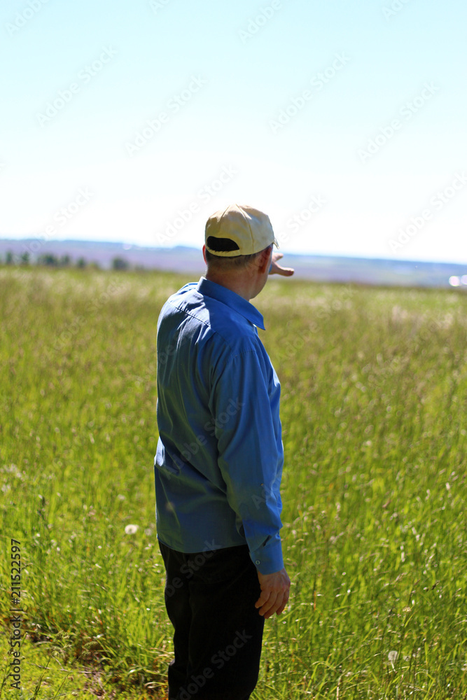 Man on the bright green field looking into the distance
