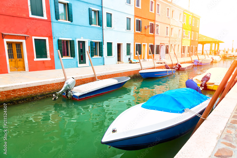 Colorful houses and boats in Burano island with sunlight near Venice, Italy. Popular and famous tourist place