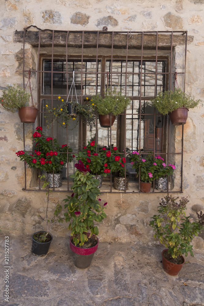 A rustic wall and window with colorful flower pots in Datca, Turkey