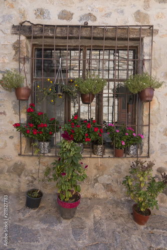 Fototapeta Naklejka Na Ścianę i Meble -  A rustic wall and window with colorful flower pots in Datca, Turkey
