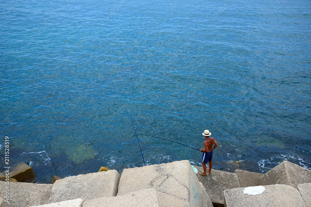 Cádiz, Spain - June 21, 2018: A man trying to fish on the coast of Cádiz.