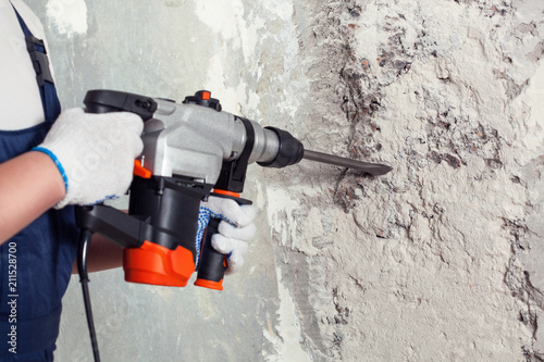 Canvastavla The builder with hammer drill perforator equipment making hole in wall at construction site