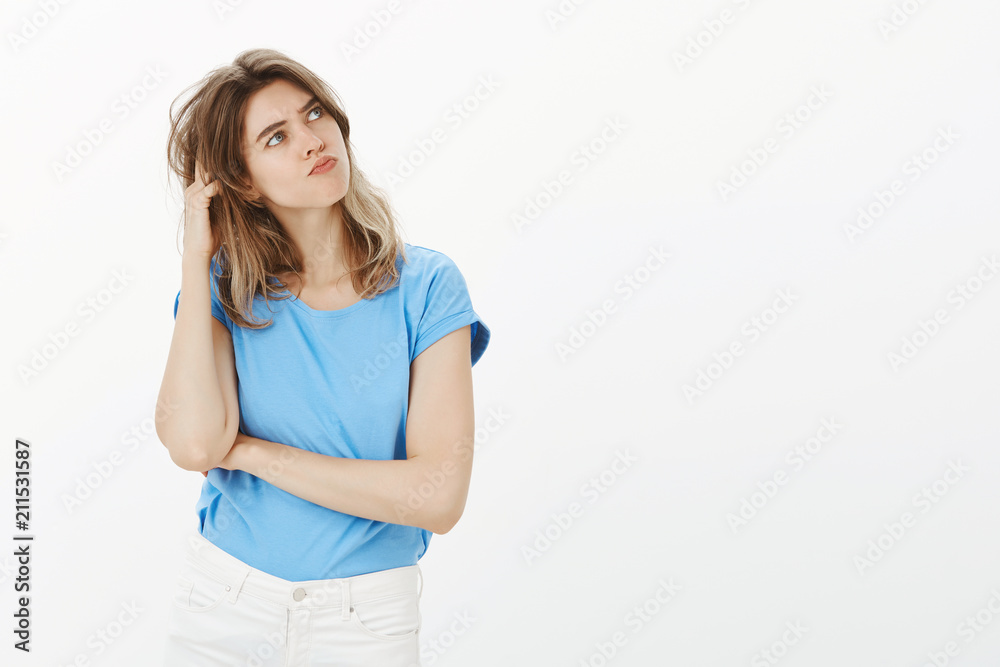 Let me think about it. Cute adult european woman with blond hair, scratching head and tilting while looking at upper right corner with serious troubled expression, making decision or plan Let me think about it. Cute adult european woman with blond hair, scratching head and tilting while looking at upper right corner with serious troubled expression, making decision or plan