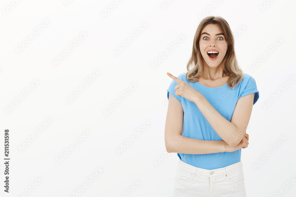 Girl has not seen anything better. Portrait of impressed happy young woman with blon hair, smiling and dropping jaw, pointing at upper left corner, being amused and amazed seeing something fatntastic Girl has not seen anything better. Portrait of impressed happy young woman with blon hair, smiling and dropping jaw, pointing at upper left corner, being amused and amazed seeing something fatntastic