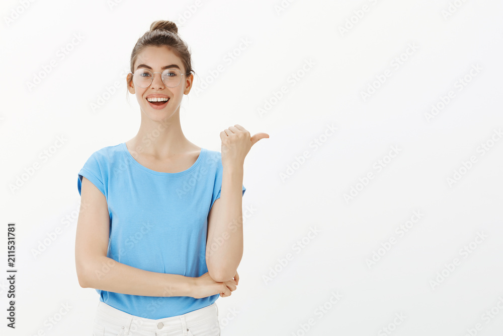 Meet my friend. Happy carefree european woman in bun and glasses, pointing right with thumb and smiling broadly, discussing interesting and positive news and directing at guy who involved in it Meet my friend. Happy carefree european woman in bun and glasses, pointing right with thumb and smiling broadly, discussing interesting and positive news and directing at guy who involved in it