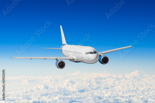 Passenger plane fly on a hight above clouds and blue sky.