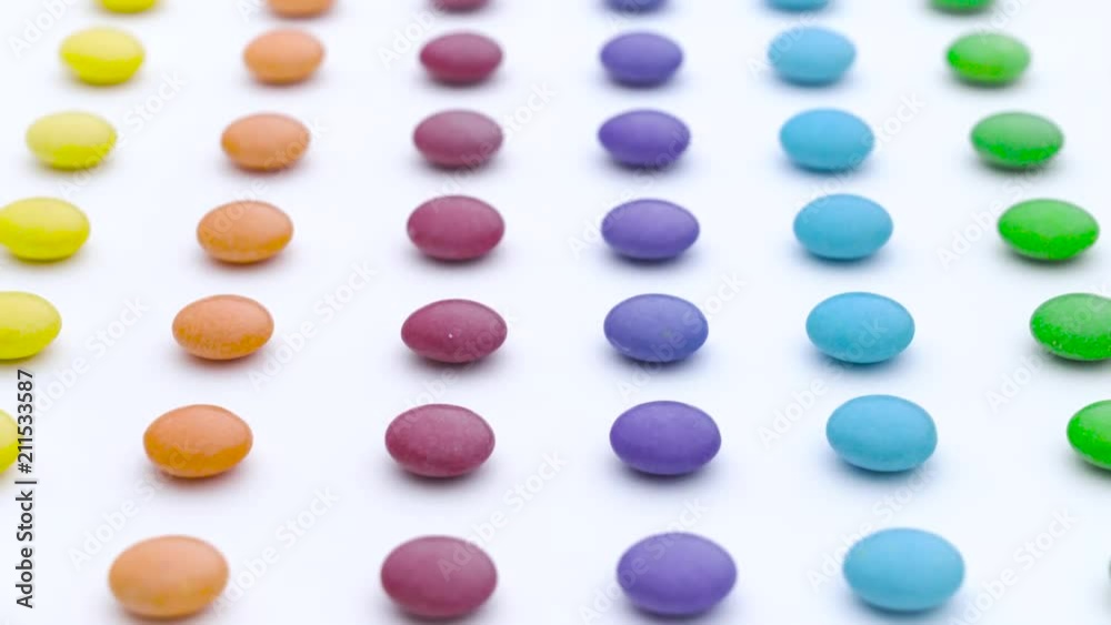 Colorful sweet round candies rows are moving vertically on the white background. Colorful sweet round candies rows are moving vertically on the white background.