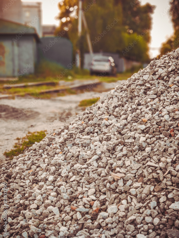 A pile of gravel for construction is on a village street. A pile of gravel for construction is on a village street.