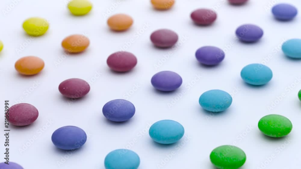 Colorful sweet round candies rows are moving diagonally on the white background. Colorful sweet round candies rows are moving diagonally on the white background.