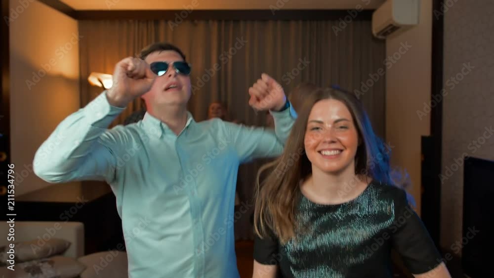 Young married couple funny dancing and drinking at evening party, slow motion UltraHD shot. MAny guests at private birthday soiree.