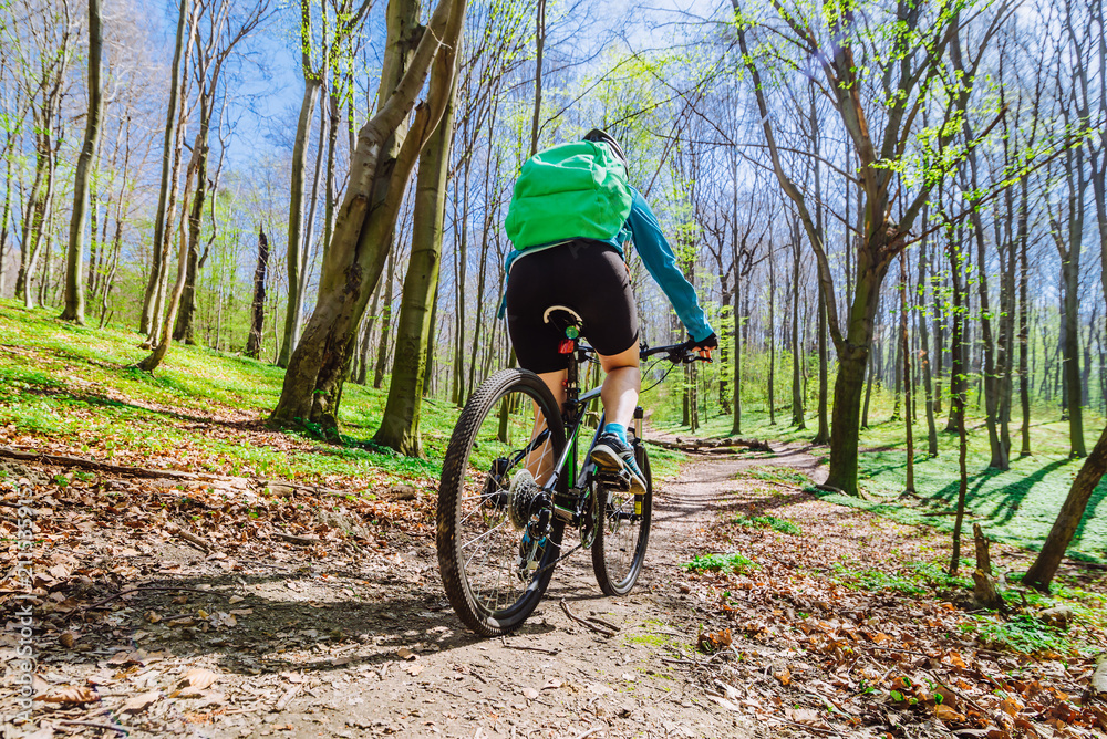 Fototapeta premium young woman ride bicycle in forest by trail