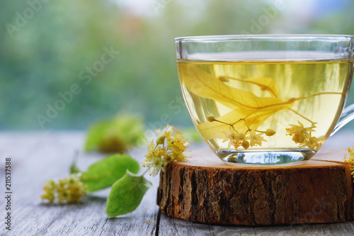 Cup of fresh tea made from linden leaves on a wooden stand close-up with space for text