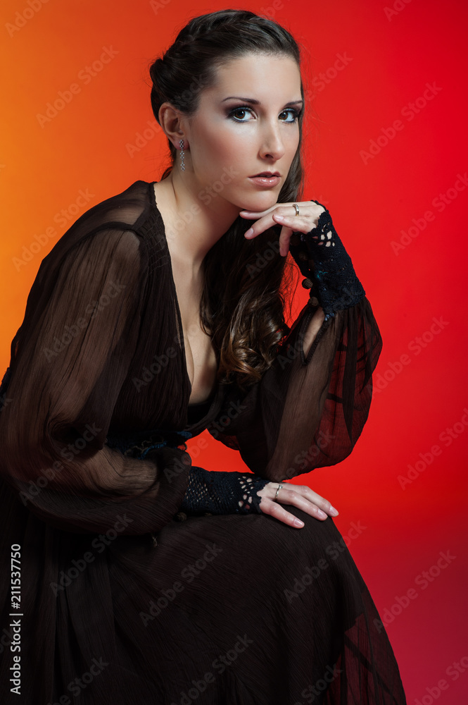 Young caucasian courtisam brunette poses for a sexy sweetie meditation in studio with red and yellow background