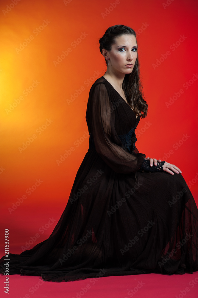 Young caucasian courtisam brunette poses for a sexy sweetie meditation in studio with red and yellow background Young caucasian courtisam brunette poses for a sexy sweetie meditation in studio with red and yellow background