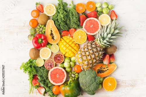 Fruits and vegetables rich in vitamin C background pattern  oranges mango grapefruit kiwi kale pepper pineapple lemon sprouts papaya broccoli  on white table  top view  copy space selective focus